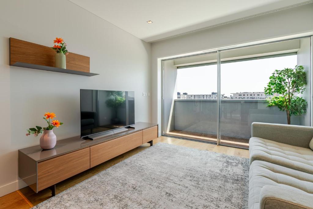 a living room with a tv and a large window at Stylish Home with Balcony & Garage by HostWise in Porto