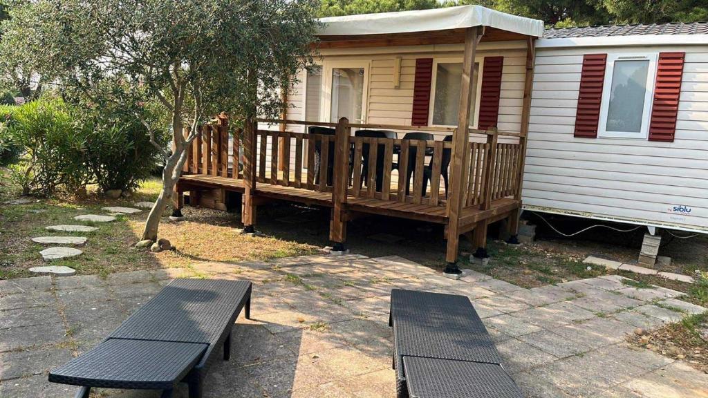a house with a porch and two benches in front of it at MOBILHOME Margueritte in Lattes