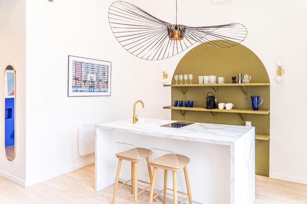 une cuisine avec un comptoir blanc et des tabourets dans l'établissement Cocon Gare Perrache, à Lyon