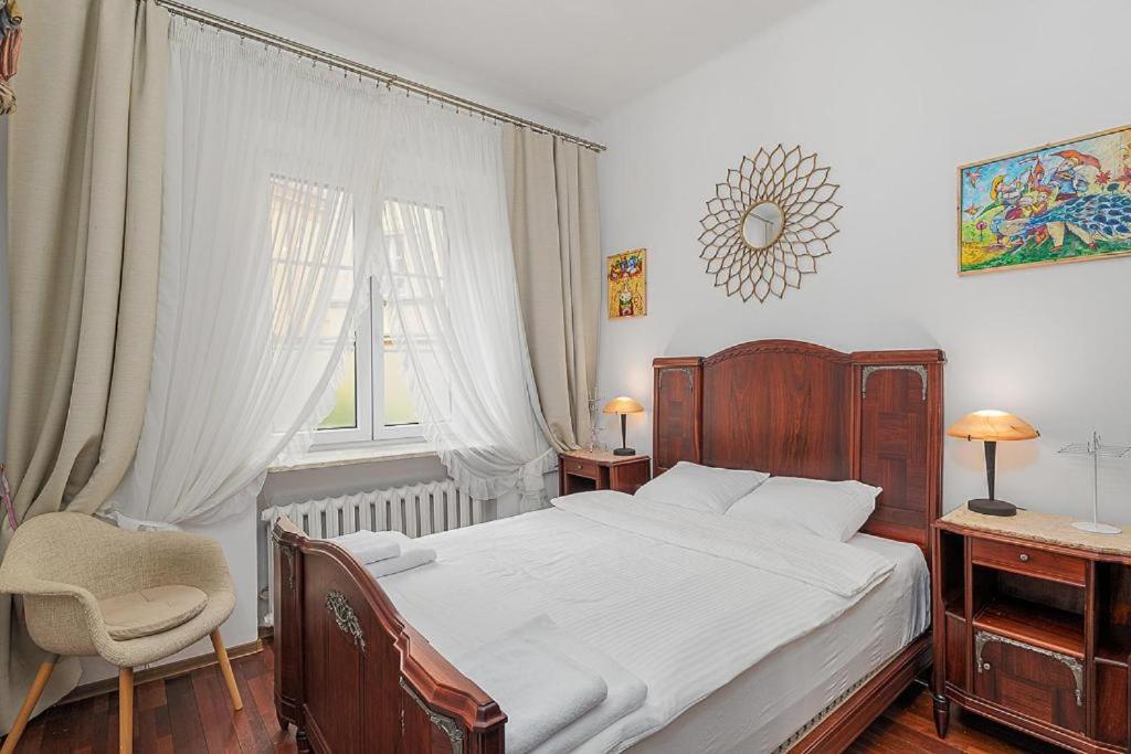 a bedroom with a bed and a chair and a window at Rynek Nowego Miasta 27 by NYX Apart in Skorka
