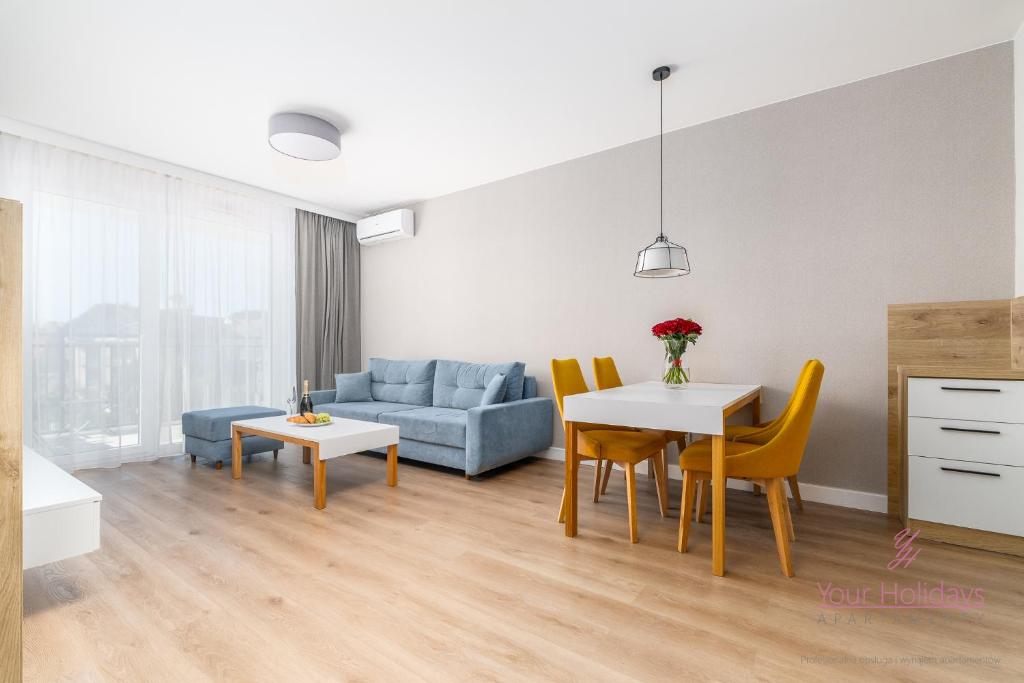 Una sala de estar con un sofá azul y una mesa y sillas. en Your Holidays Bel Mare 217D, en Międzyzdroje