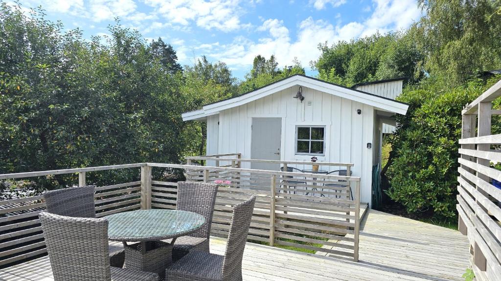 un patio avec une table et des chaises sur une terrasse dans l'établissement Cottage near sea, art & fishing villages on Tjorn, à Klövedal