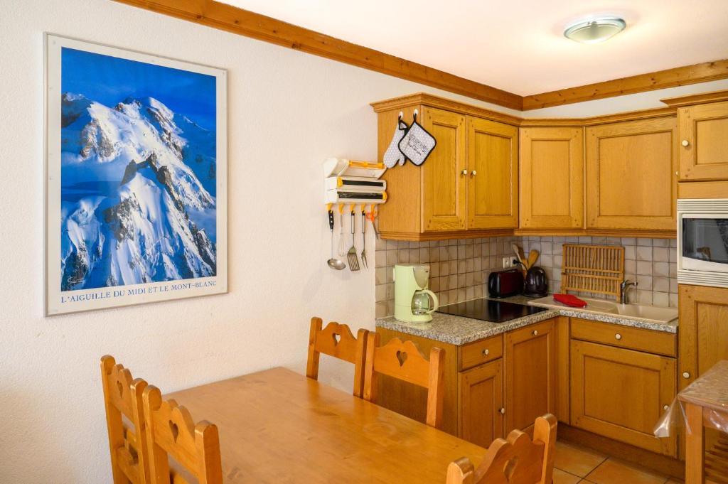 - une cuisine avec des placards en bois et une table à manger dans l'établissement Le Névé, à Saint-Gervais-les-Bains