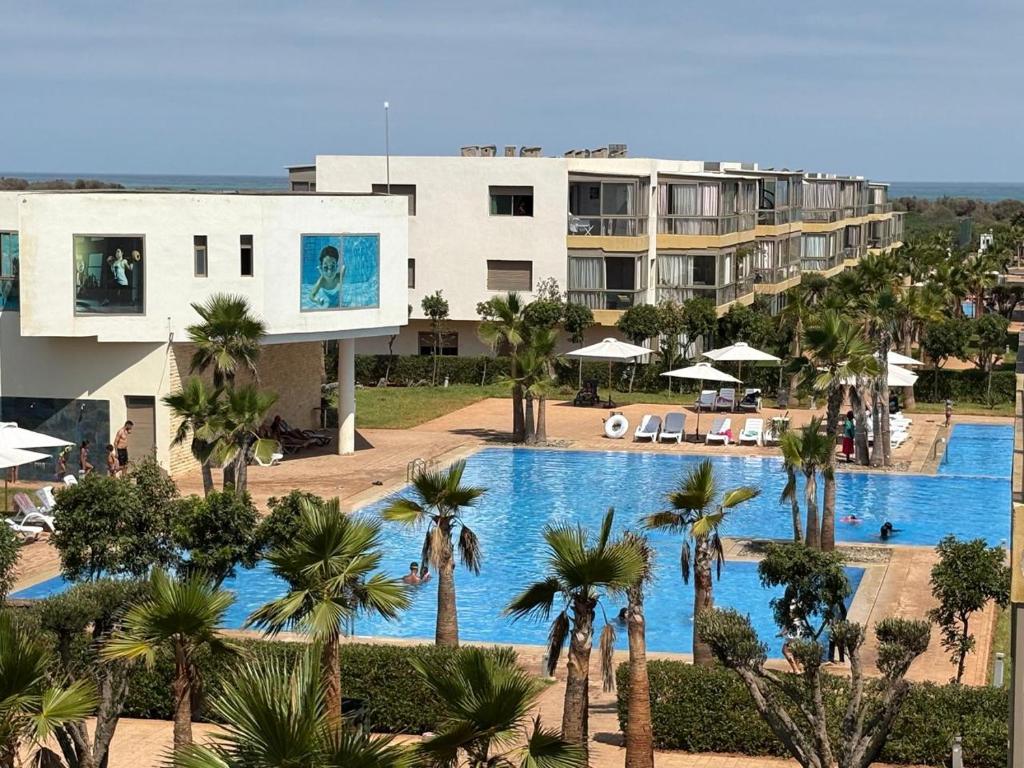 a view of a resort with a swimming pool and palm trees at Appartement vue piscine - Pour Famille - Blue Beach SIDI RAHAL in Sidi Rahal
