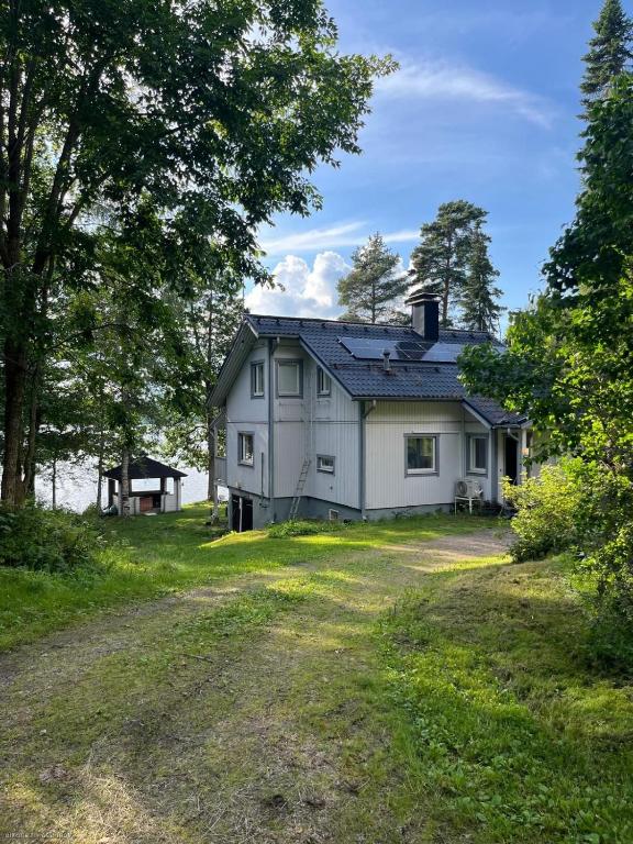 a white house on a hill next to a dirt road at Lake house 56 km from Helsinki in Lohja