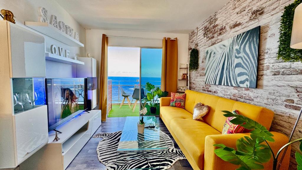 a living room with a yellow couch and a tv at Ocean Soul Apartment in Santa Cruz de Tenerife