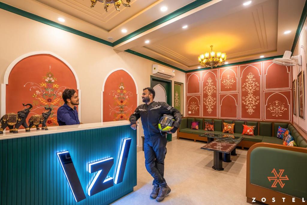 a man standing at a bar in a hotel lobby at Zostel Agra in Agra