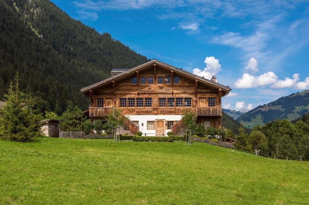 a wooden house on a hill in a field at Elegant Alpine Chalet with Spa in Lauenen