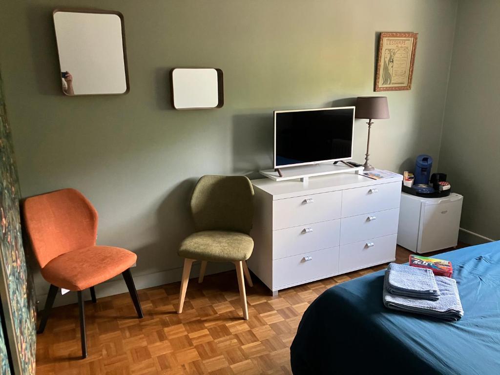 a bedroom with a dresser with a tv and a chair at Chambre indépendante 10min circuit 24h tramway in Le Mans