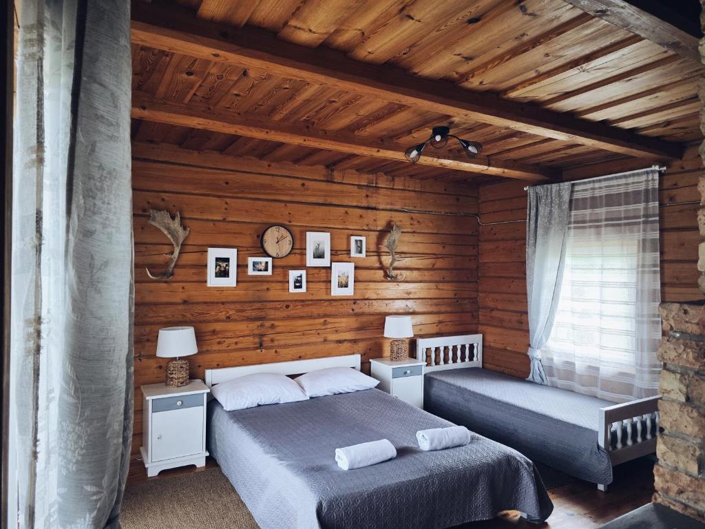 two beds in a room with wooden walls at Sodyba "Vytauto kaimas" Aukštadvaris in Aukštadvaris