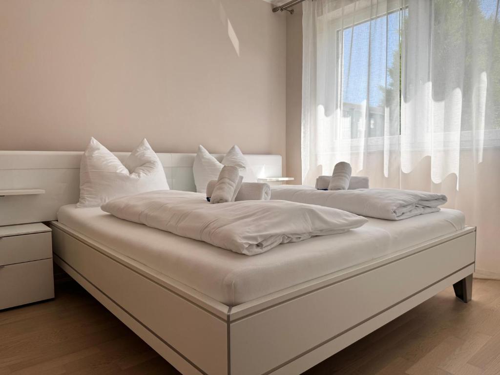 two beds in a white room with a window at FAAKER SEE HIDEAWAY - Apartment mit Garten in Faak am See