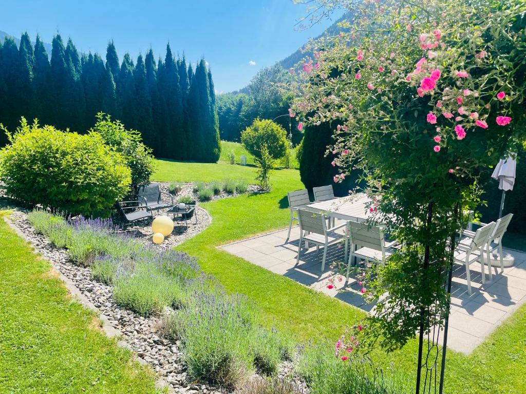 a garden with a table and chairs and flowers at Wohlfühlpension Kreischberg inklusive MurauGästeCard in Sankt Georgen ob Murau