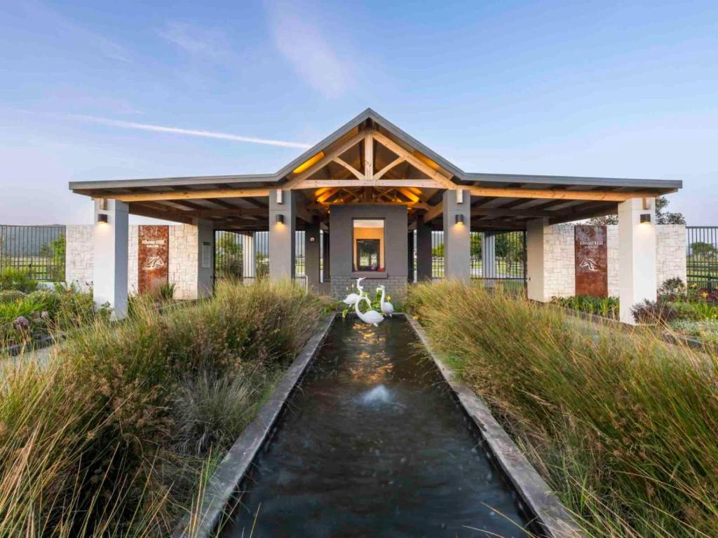 a house with a pond in front of a building at Rhone Hill Polo Club in Plettenberg Bay