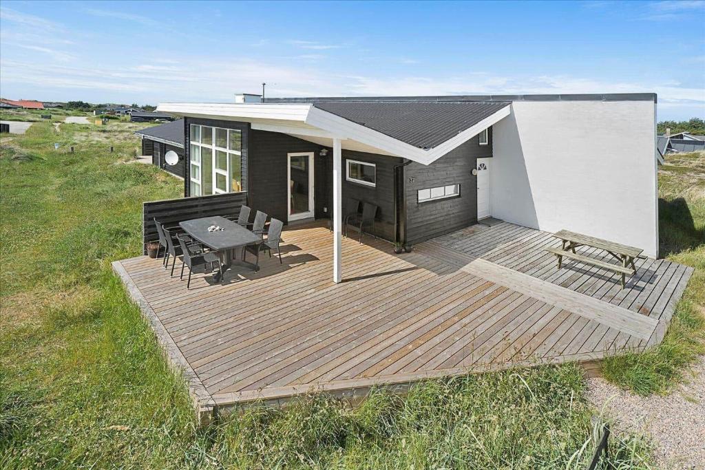 a house with a wooden deck with a table and benches at 941-Thisted-Klitstien-37 in Torsted