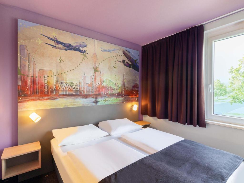 a bedroom with a bed with a painting on the wall at B&B Hotel Düsseldorf-Airport in Düsseldorf