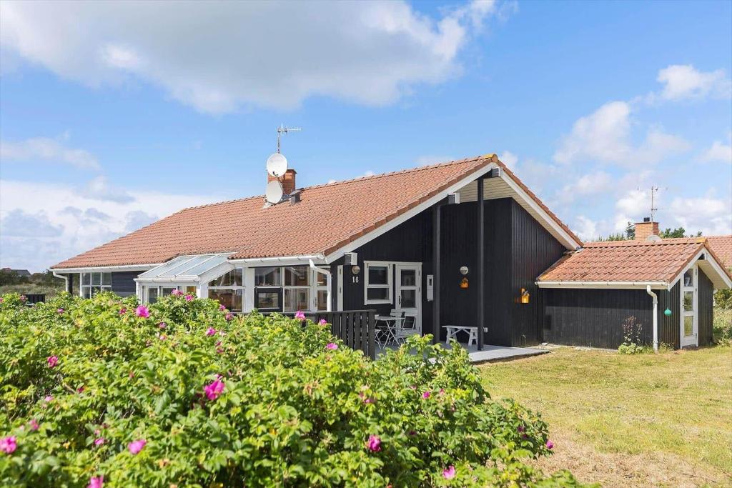 a black house with a red roof and some flowers at 546-Thisted-Kuttervej-16 in Thisted