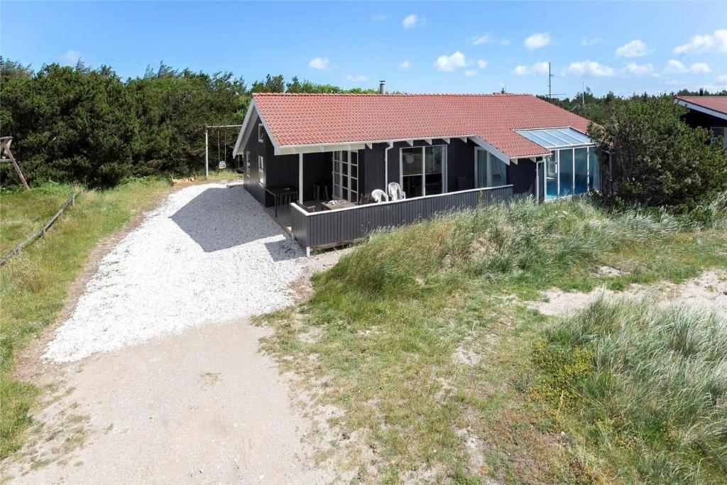 une maison sur une plage avec un chien assis sur un porche dans l'établissement 975-Thisted-Klitstien-45, à Torsted