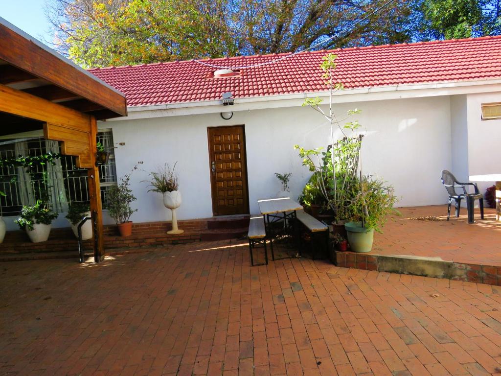 ヨハネスブルグにあるNorthcliff Green Houseの白い家(椅子と植物のあるパティオ付)