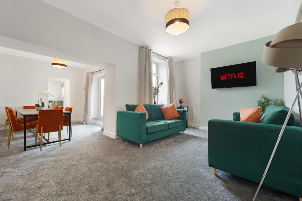 Quarrington HillにあるNew! 4BR in Hill top Houseのリビングルーム(緑のソファ2台、テーブル付)