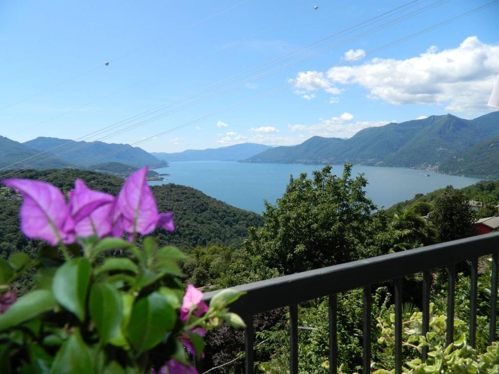 una vista di un lago da un balcone con fiori viola di Lago Maggiore Holiday House with Panoramic Views a Dumenza