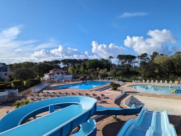 un complexe avec deux piscines avec chaises et un toboggan dans l'établissement Soleillade Studio cabine avec terrasse 2 adultes 1 enfant, à Talmont-Saint-Hilaire