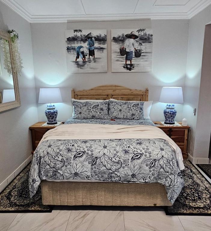 a bedroom with a bed with two lamps and pictures on the wall at Upstairs R-4 Self Catering Unit in White River