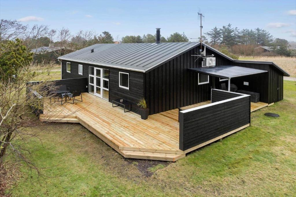 a black house with a wooden deck in a field at 1322-Snedsted-Lykkens-Hab-21 in Snedsted