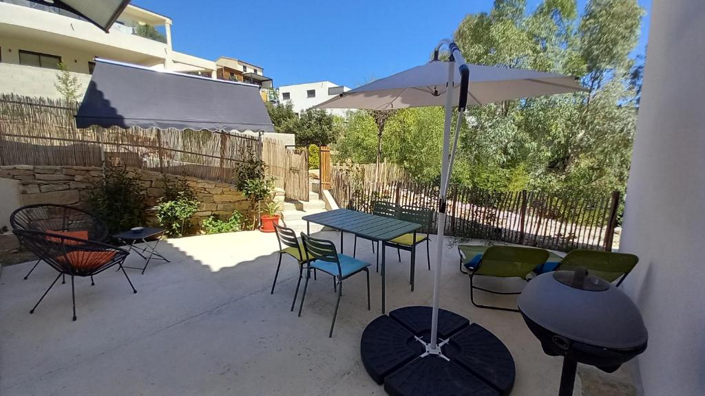 eine Terrasse mit Tisch und Stühlen und einem Sonnenschirm in der Unterkunft Appartement avec terrasse dans maison individuelle in Ceyreste