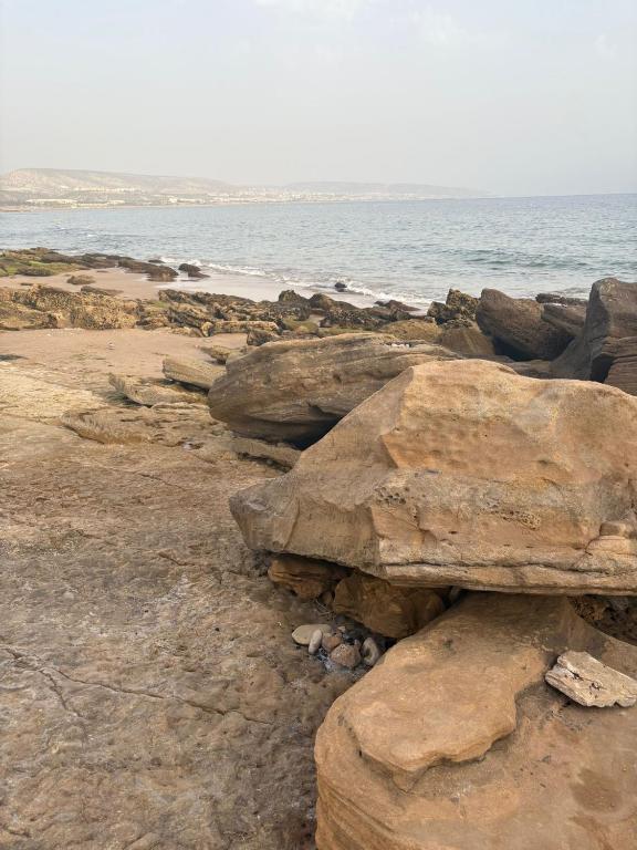 a group of rocks on a beach near the ocean at Seagull house in Aourir
