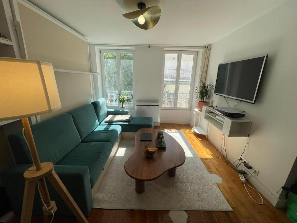 uma sala de estar com um sofá verde e uma mesa em Studio Cosy au charme Parisien - Butte aux cailles em Paris