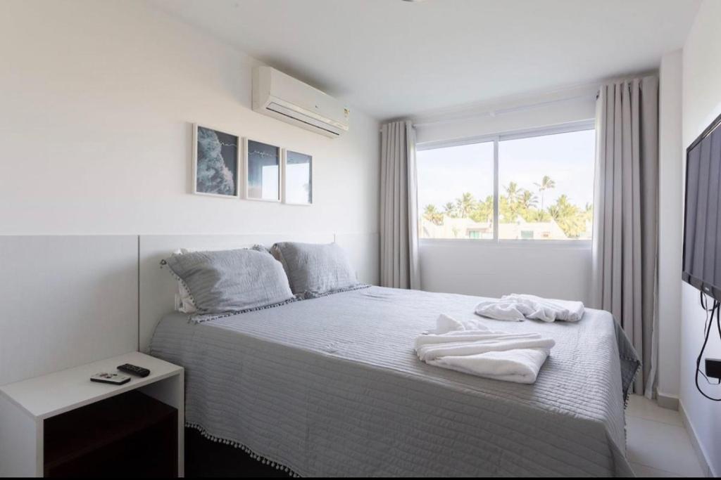 a white bedroom with a bed and a window at Porto Plaza Flat Service Apt 309 in Porto De Galinhas
