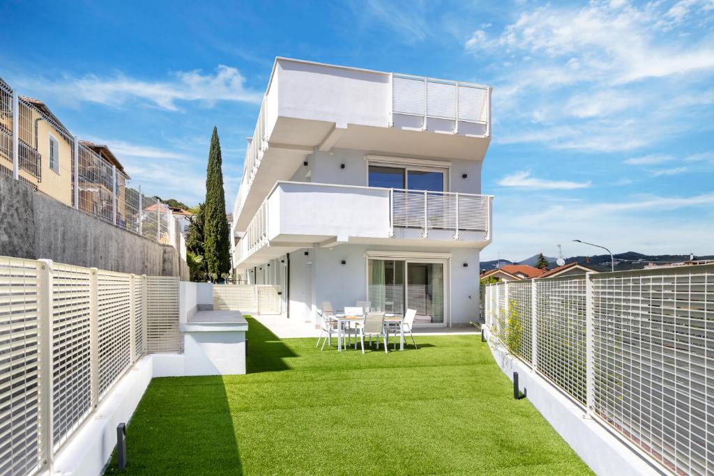 una casa blanca con un patio con césped verde en Hostdomus-La casa degli artisti-Michelangelo-Giotto-Raffaello, en Andora