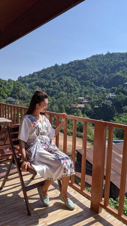 a woman sitting on a bench on a deck at ปิล๊อกพอเพลิน-pilokporploen in Ban Pilok Khi