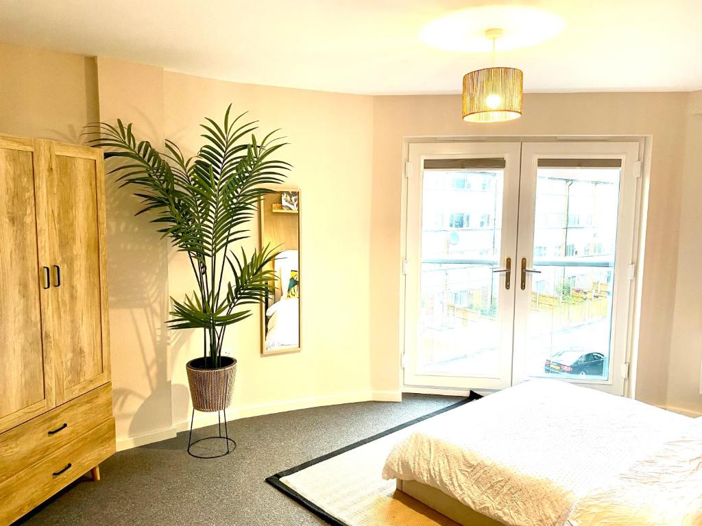 a bedroom with a bed and a potted plant at Safari 2 Bedroom Condo with Free Secure Parking in Manchester