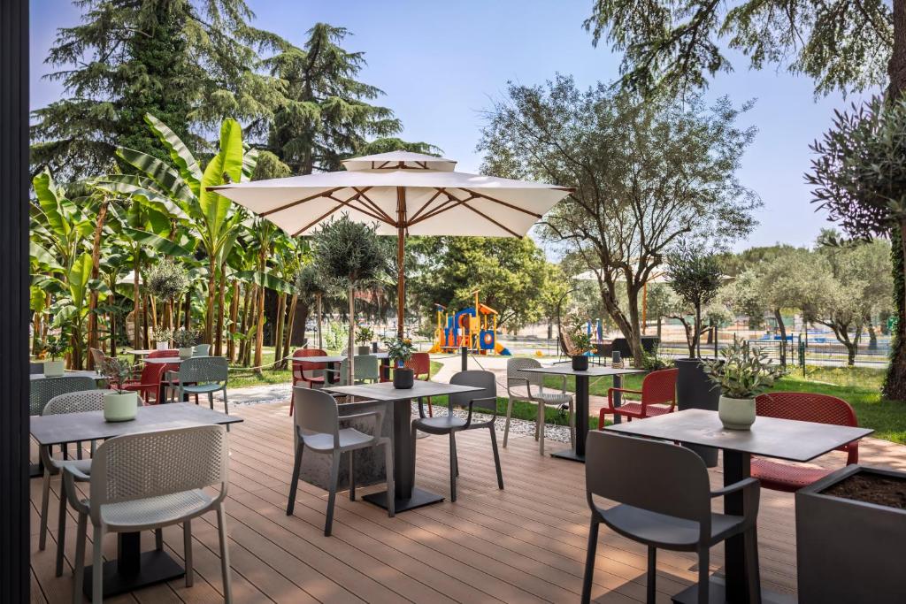 eine Terrasse mit Tischen und Stühlen und einem Sonnenschirm in der Unterkunft Remisens Hotel LUCIJA in Portorož