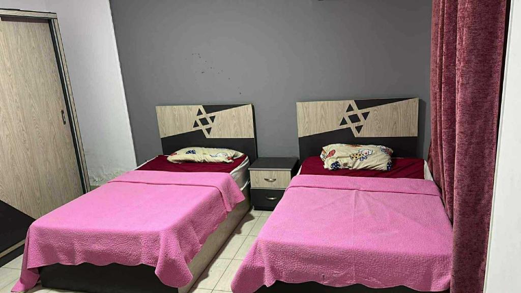 Dos camas en una habitación con sábanas rosas. en Dar Hadla, en Seis de Octubre