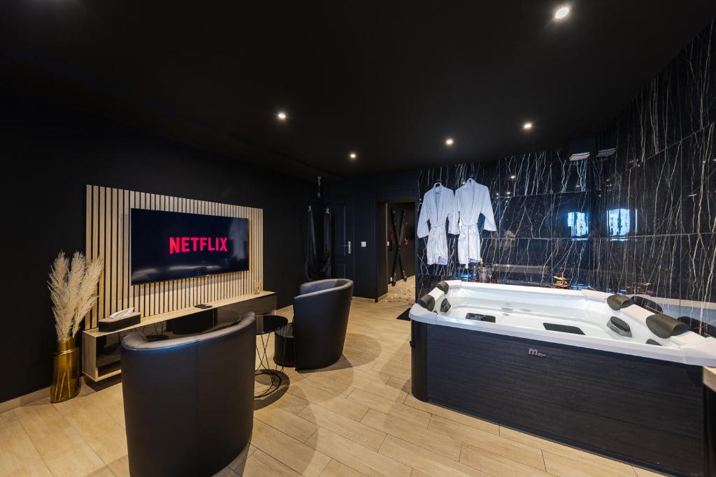 a bathroom with a bath tub and a tv in a room at SecretBlackRoom in Villecresnes