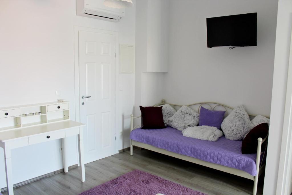 a white room with a purple couch and a tv at Adriona apartments with parking in Makarska