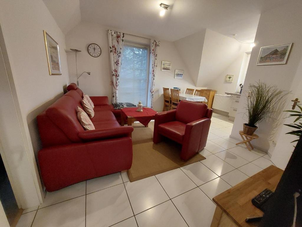 a living room with a red couch and a chair at Birkenquartier in Zingst