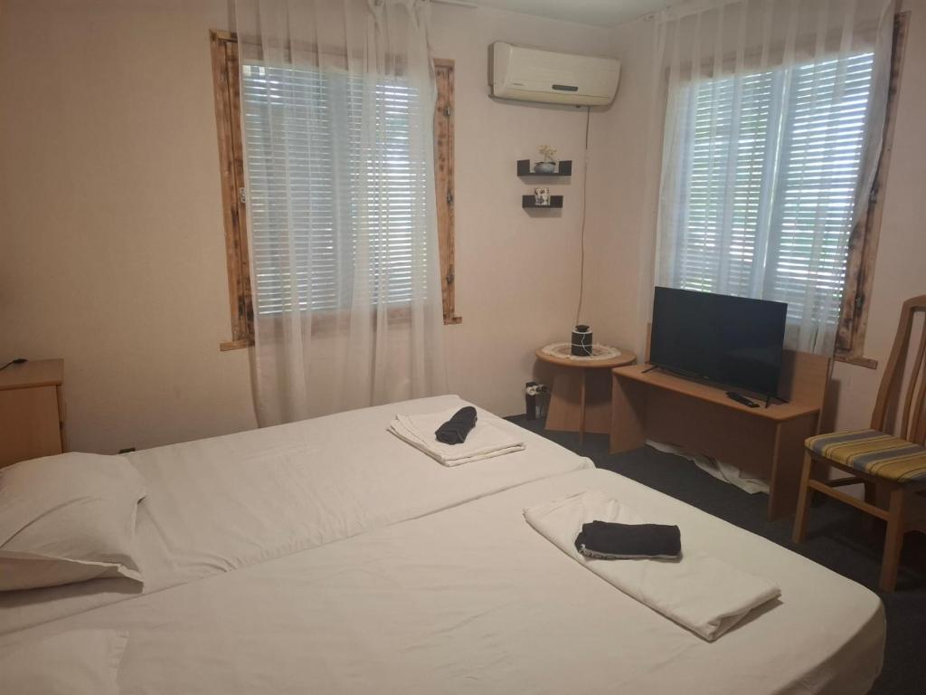 a bedroom with a white bed and a television at Bunaglows Panoramic Beach Village in Balchik