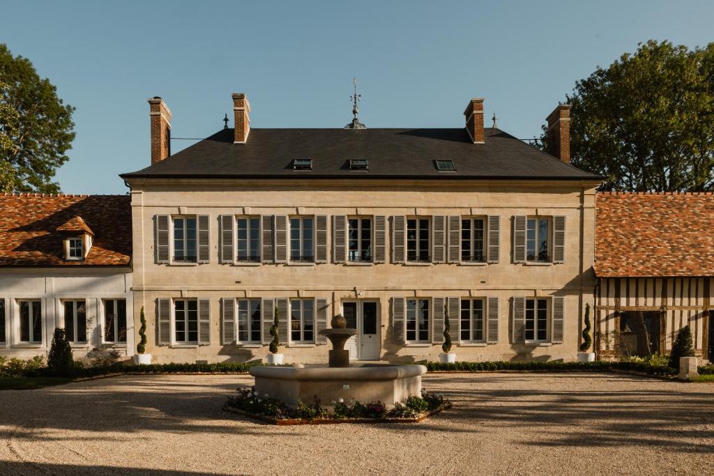 Une grande maison blanche avec une fontaine en face de celle-ci dans l'établissement Le Clos des Martines, Maison d'exception, à Écos