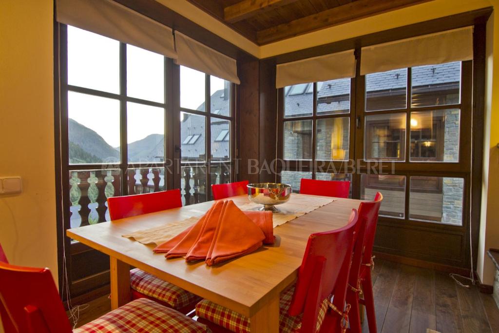 a dining room with a wooden table and red chairs at Apartarent 1500 - Apartamento Acebo in Baqueira-Beret