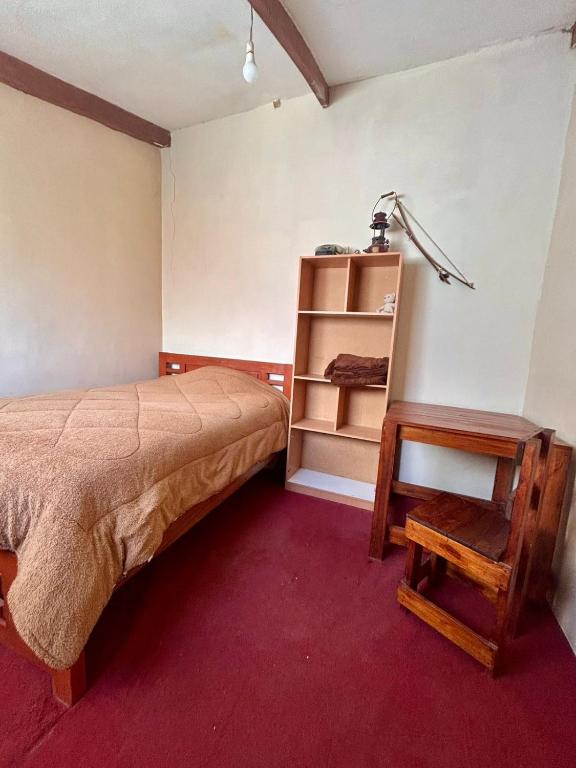 a bedroom with a bed and a table and a shelf at Casa de Liz in Sucre