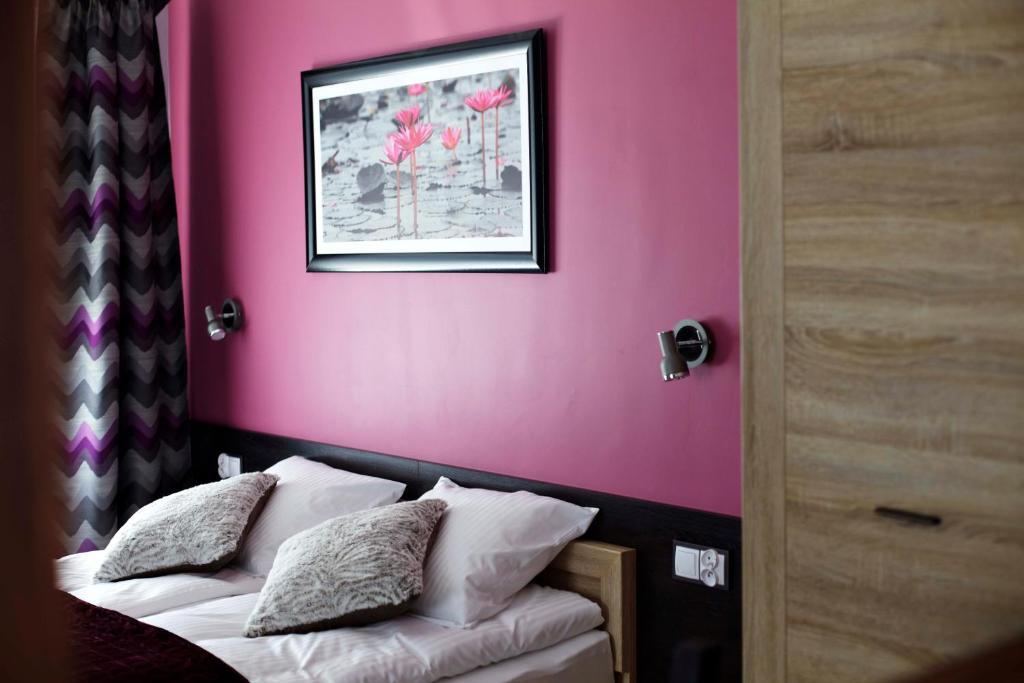 a bedroom with a pink wall and a bed with pillows at Comfort-24 in Słupca