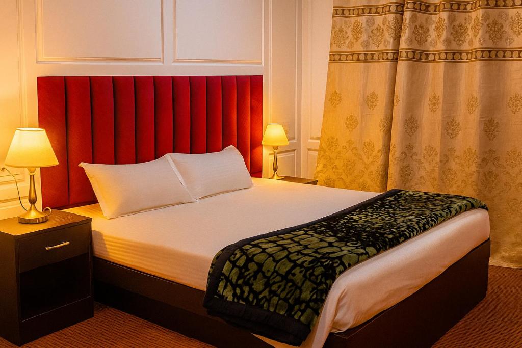 シュリーナガルにあるKoh E Noshの赤いカーテン付きのベッドが備わるホテルルームです。