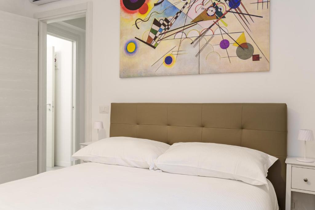 a bedroom with a white bed with a painting on the wall at Actus Palace Rooms by Ghor in Rome