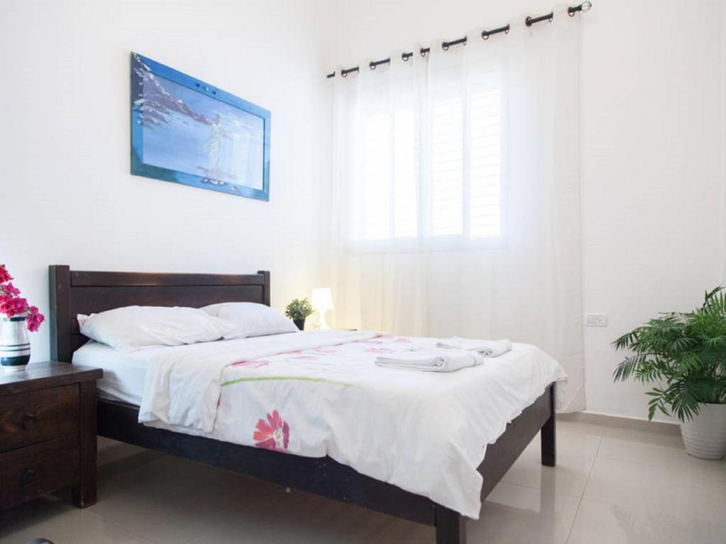 a bedroom with a bed with white sheets and a window at Alona's Apartments in Haifa