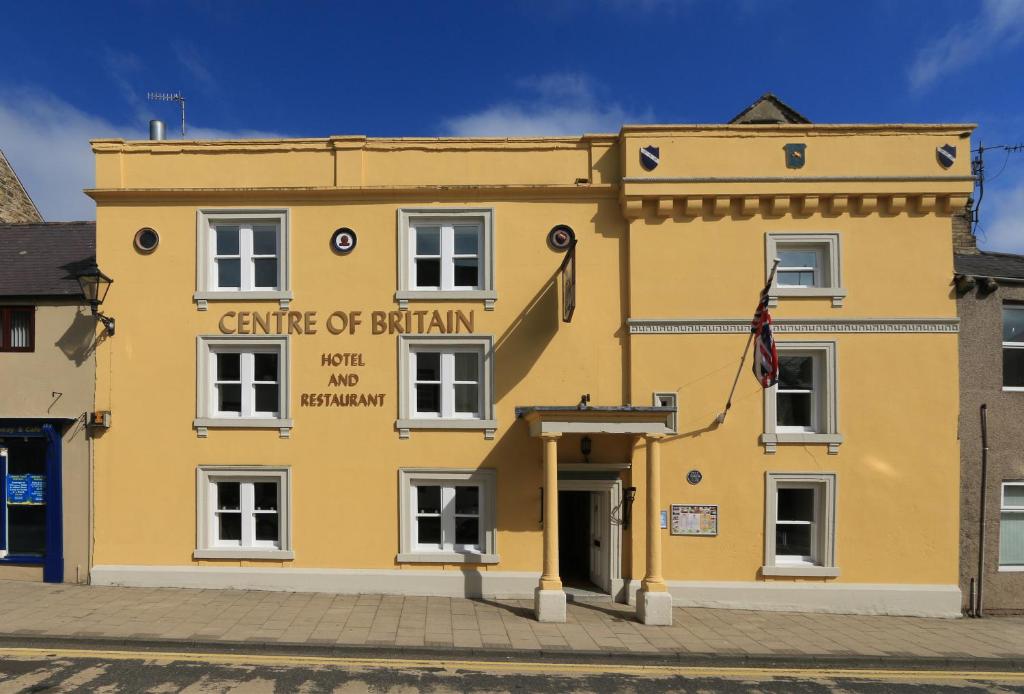 um edifício amarelo com uma bandeira em frente em Centre Of Britain Hotel em Haltwhistle