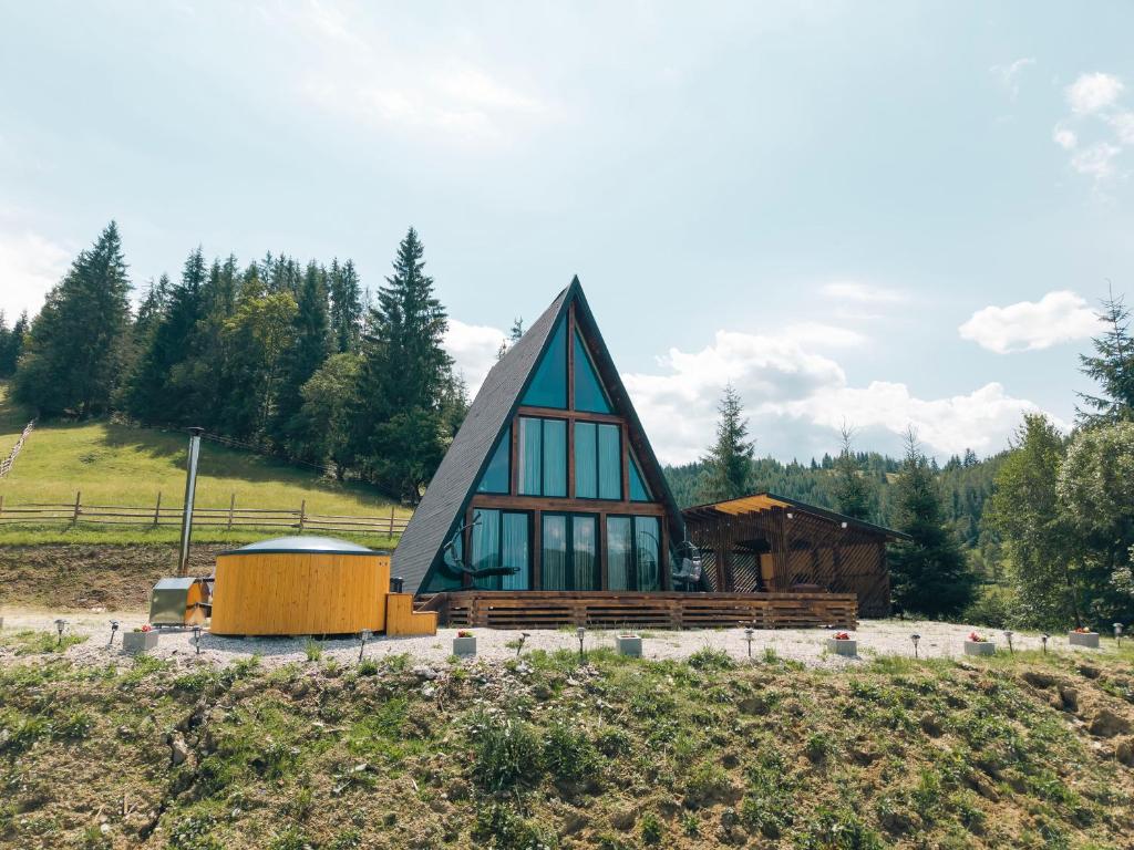 a small house with a pointed roof on a hill at NordiKaban A-Frame Vatra Dornei in Ortoaia