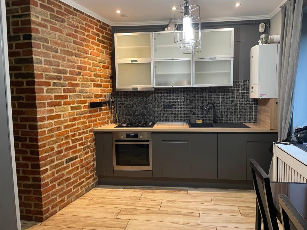 a kitchen with white cabinets and a brick wall at Cazare Bârlad 4 in Bîrlad